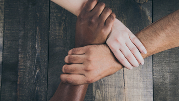 hands of three different people from different backgrounds interlocked